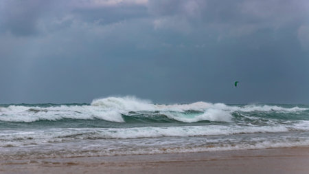 Surfer's parachute in a stormy sky over the foamy waves of the Mediterranean Sea. Israel