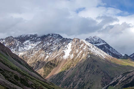 Mountain view with snow-capped peaks against a cloudy sky.Kyrgyzstanの写真素材