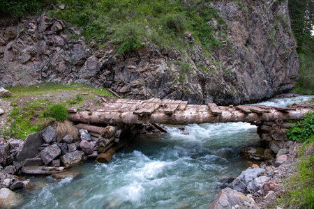 Mountain river with a wooden bridge between stony hills. Kyrgyzstan
