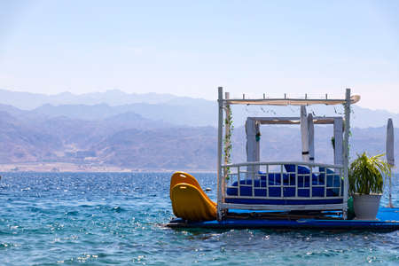 A pier floating on the water with sunbeds for relaxation and surfboards on a background of colorful mountains. Eilat Bay of the Red Sea. Israelの写真素材
