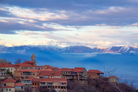 View of Sighnaghi city standing on a hill against the backdrop of snow-capped mountains and sky in...