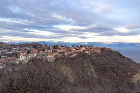 View of Sighnaghi city standing on a hill against the backdrop of snow-capped mountains and sky in...