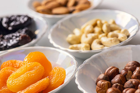 Dried fruits apricots and prunes, various nuts and almond kernels in plates close upの写真素材