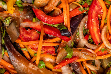 Top view on vegetable salad of eggplant, carrots, onions, peppers with oriental spices close-upの写真素材