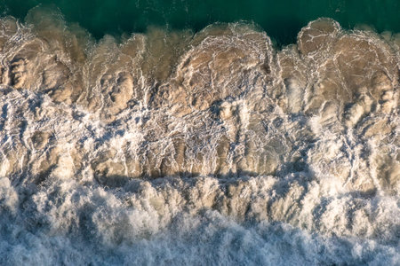 Top view of patterns of white foam from the impact of ocean waves on coastal rocks. South Africa
