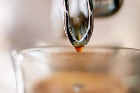 Coffee machine dripping directly on a glass cup in close up concept.の写真素材