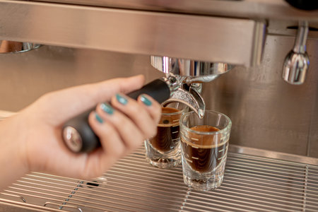 Barista woman serving delicious coffee with a coffee maker in two small glassesの写真素材