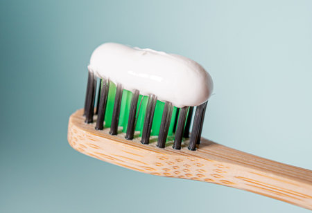 Ecological toothbrush with biodegradable black and green bristles with toothpaste on top and blue...