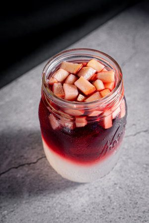 Delicious sangria with lemonade and apple pieces served in a glass tumbler on a marble table.の写真素材