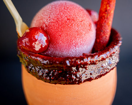Delicious cantarito with tequila, strawberry snow, chili powder and traditional Mexican candy, with...