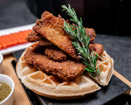 Exquisite waffle with breaded chicken, papaya on the bottom and sauces on the side.の写真素材