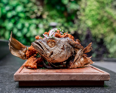 Delicious Mexican fried fish with red onion and cilantro, served on a board, with a background of...