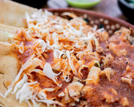 Exquisite golden tacos of pork carnitas Guadalajara Mexican style, accompanied by maciza and cabbage, served in a clay dish.の写真素材