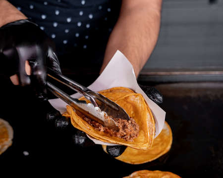 Person preparing guadalajara style birria taco with tortilla, onion and cilantro.の写真素材