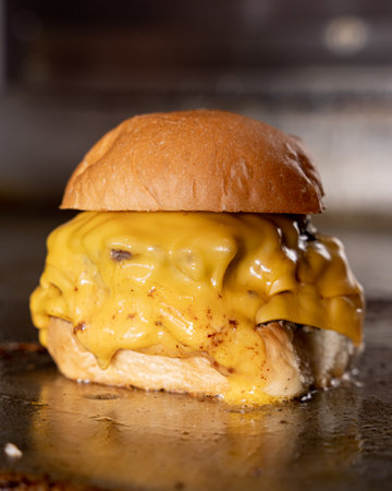 Delicious slider burger with lots of yellow cheese on a grillの写真素材