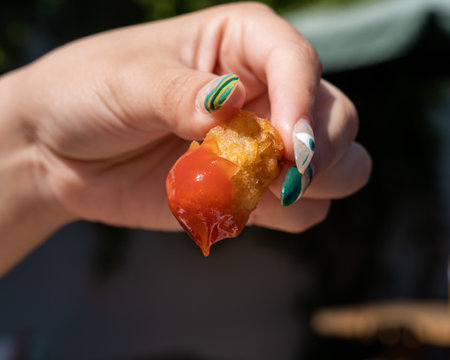 delicious potato held by a hand with ketchupの写真素材