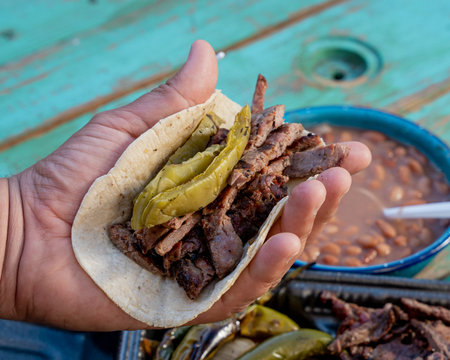 person making a delicious mexican style carne asada taco, with avocado, adas onions, molcajete...