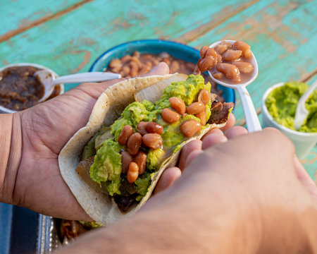 person making a delicious mexican style carne asada taco, with avocado, adas onions, molcajete...