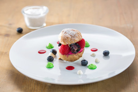 choux bun with fruits in a white plate on a wooden table