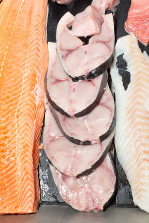 salmon and slice of swordfish at a fishmonger on icy backgroundの写真素材