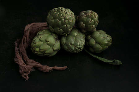 Three artichokes tied with a cloth on a dark backgroundの写真素材