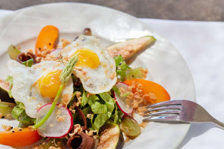 Salad plate with smoked duck breast and fried eggs on the tableの写真素材