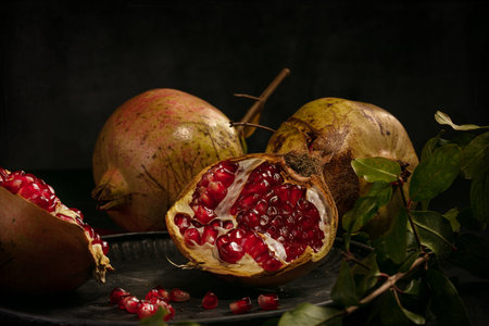 Pomegranate and open pomegranate in a plate on a dark table