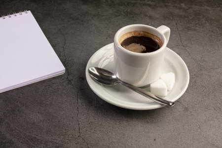 Coffee cup with a telephone and a notebook on a dark background