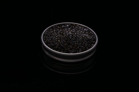 Caviar in a metal box on black background