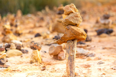 Pile of stones balanced on a piece of wood, Land Art, in natureの写真素材