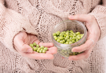Jar of raw peas in the hands of a woman with a pulloverの写真素材