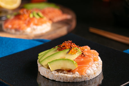 Puffed rice spread with raw salmon and avocado on a dark table