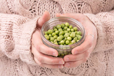 Jar of raw peas in the hands of a woman with a pulloverの写真素材