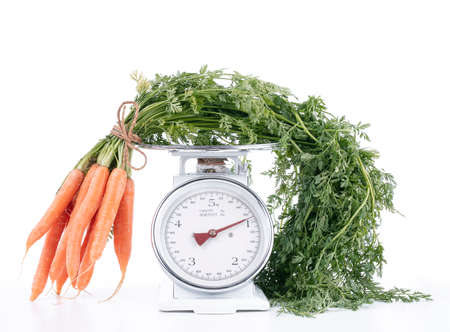 Carrot bunch with tops on a scale on a white backgroundの写真素材