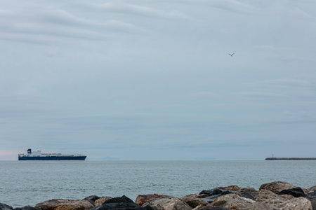 Sea in winter with a ferry returning to a port with gray clouds