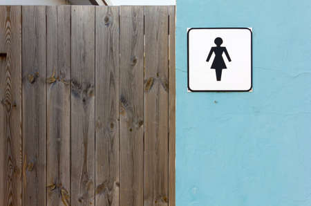 Ladies toilet sign on an exterior wall next to a wooden doorの写真素材