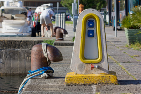 Water and eletricity distribution pedestal on a jetty next to a bollard