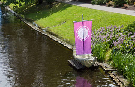 RIGA, Latvia - July 17th 2013: A model sailboat with a purple colored sail on the bank of the city canal in downtown Riga, Latvia.のeditorial素材