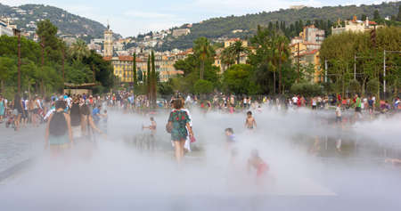 NICE, France - August 20, 2014: People having fun in the steam of a mirror fountain in a downtown city parkのeditorial素材