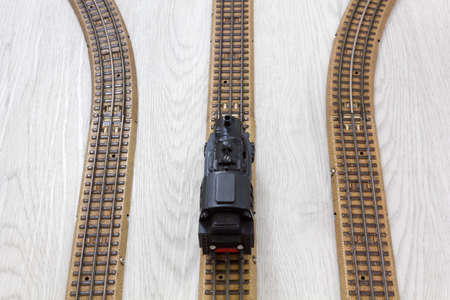 1950s vintage model steam locomotive on the rails over a wooden texture floorの写真素材