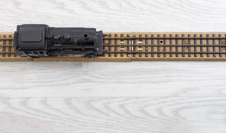 1950s vintage model steam locomotive on the rails over a wooden texture floorの写真素材