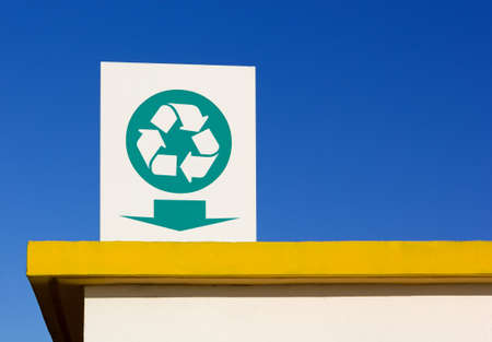Recycling symbol sign over a yellow colored roofの写真素材