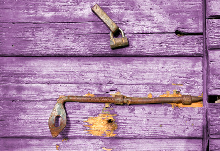 Close-up on an old purple wooden door with peeling paint and rusty lock and handleの写真素材