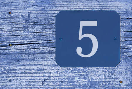 Street number 5 sign on an old blue wooden door with peeling paintの写真素材