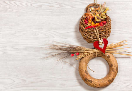 Small rustic ornamental wicker basket full of dried flowers and enriched with other decorations against a white wooden backgroundの写真素材