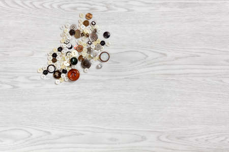Buttons of various shapes and sizes on a white wooden backgroundの写真素材
