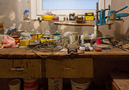 DUINO AURISINA, Italy - December 6, 2017: Very old dirty and messy garage workbench full of rusty tools, cans and boxesのeditorial素材