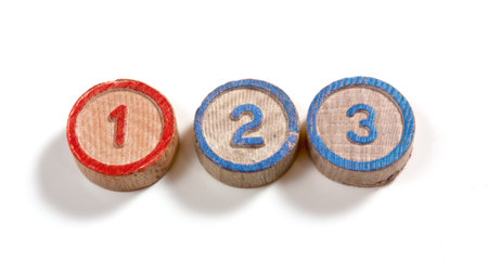 Numbers one two and three on small wooden cylinder-shaped pieces on a white background