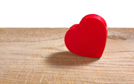 Heart-shaped red plastic box on an old wooden surfaceの写真素材
