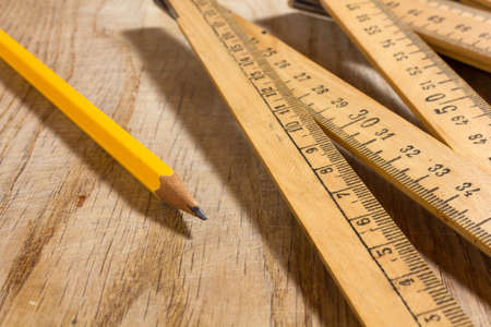 A measuring stick and a pencil on an old wooden tableの写真素材